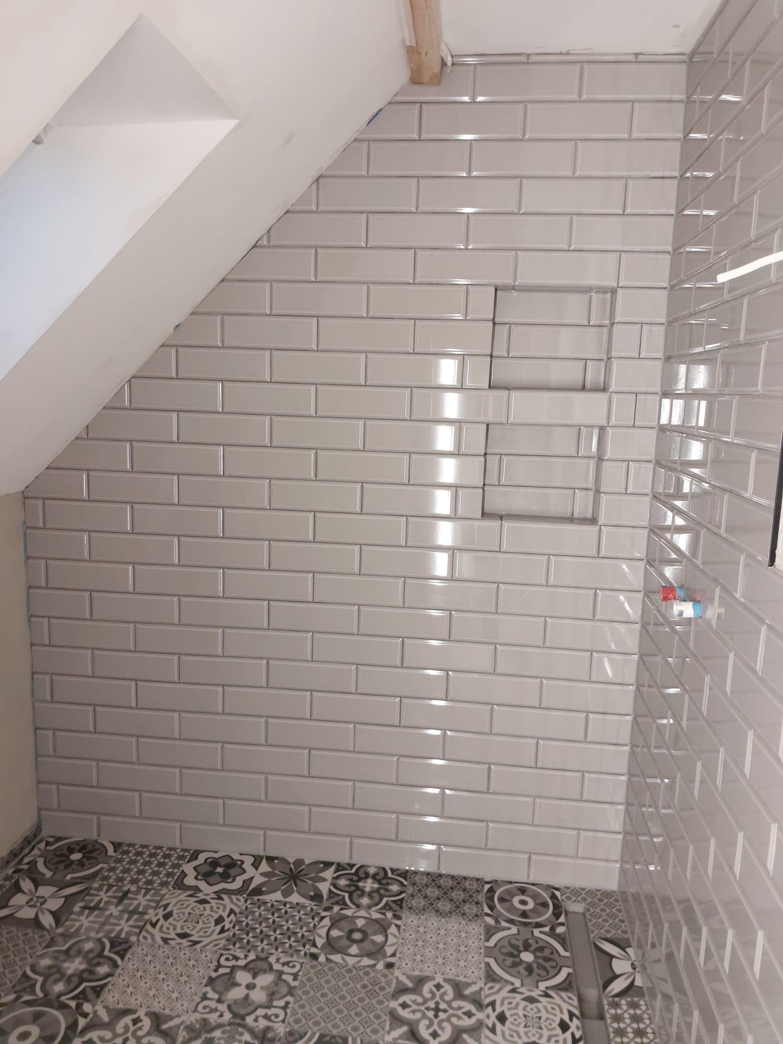 Weiße Fliesenarbeiten in einem Duschbereich mit klassischem Fugenbild